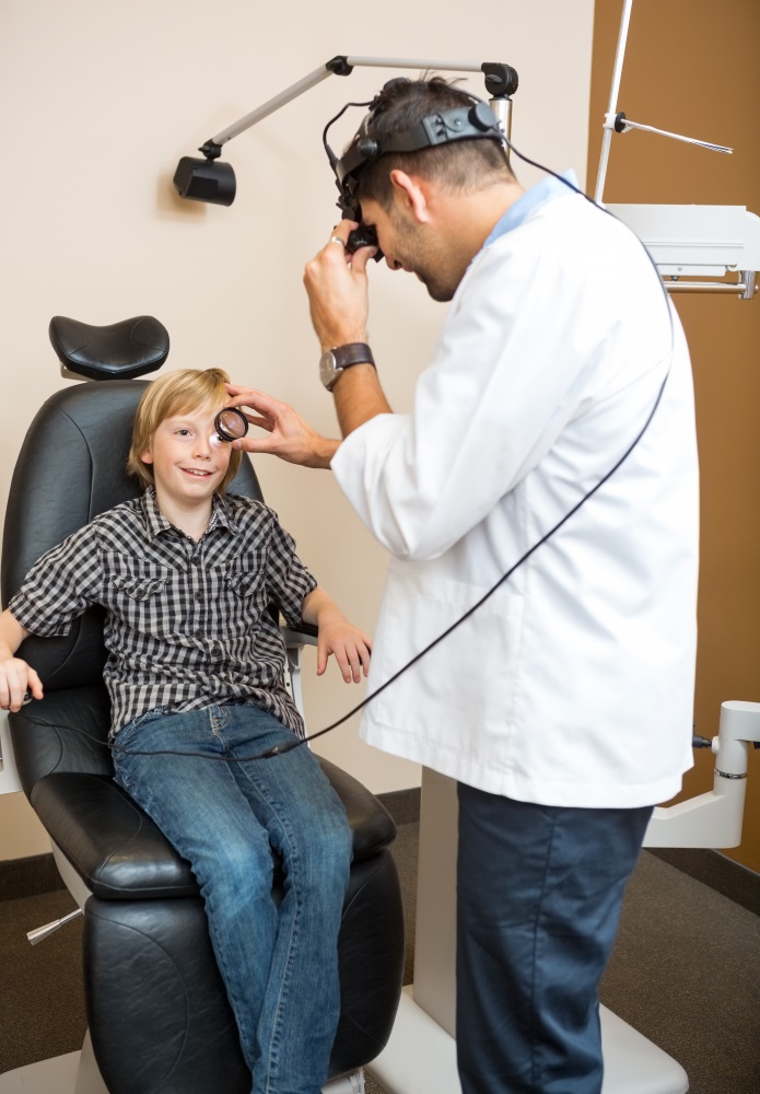 Optician Examining Boy's Eye Through Lens