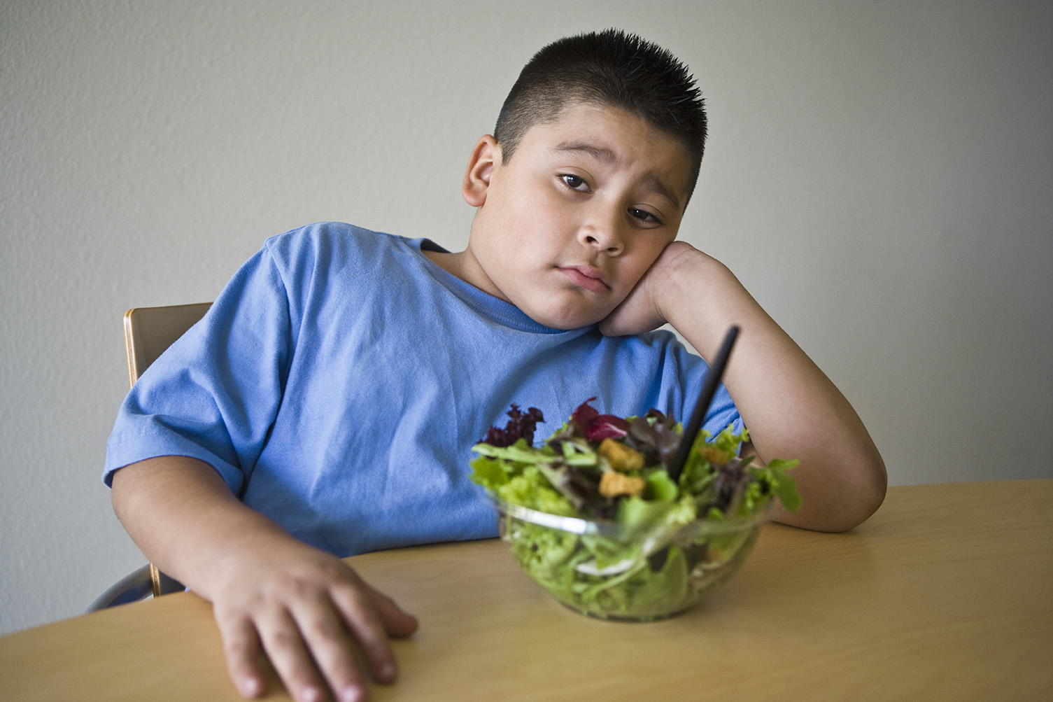 Pre-teen (10-12) boy sitting at desk with salad