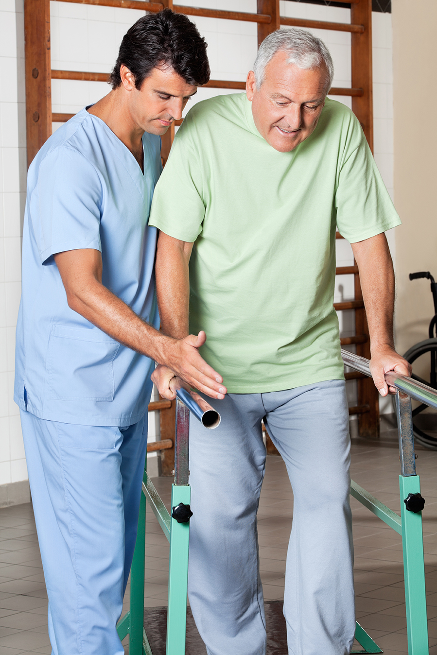 Physical therapist assisting senior man to walk with the support